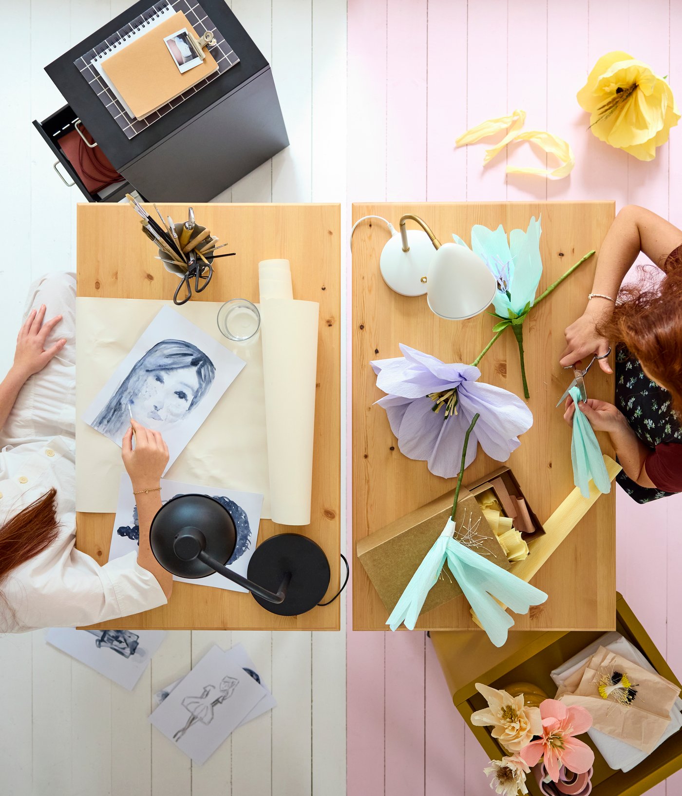 Two BOLLPOJKE desks in pine/white side by side, viewed from above, with two teens crafting and using art supplies.