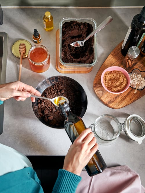 Kitchen with countertop, bowl, jar with lid, food container with lid, measuring cups, chopping board, spoons, ingredients.