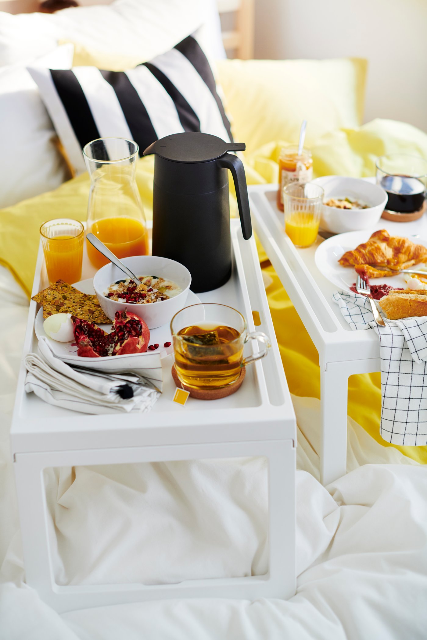 Frühstück auf zwei KLIPSK Tabletts, u. a. mit Croissants, Müsli, Orangensaft und Kaffee.