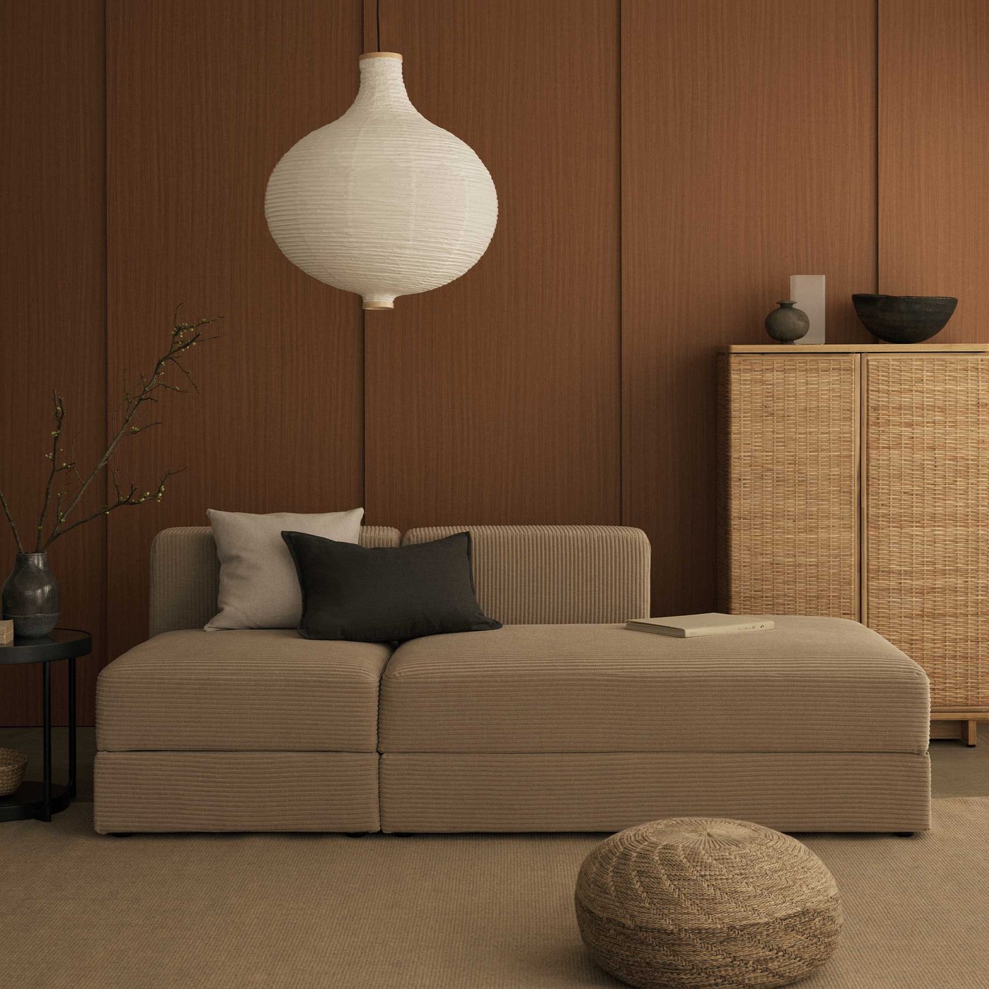 木と自然素材を基調にしたインテリアで、ベージュのローソファ、クッション、プーフがある。