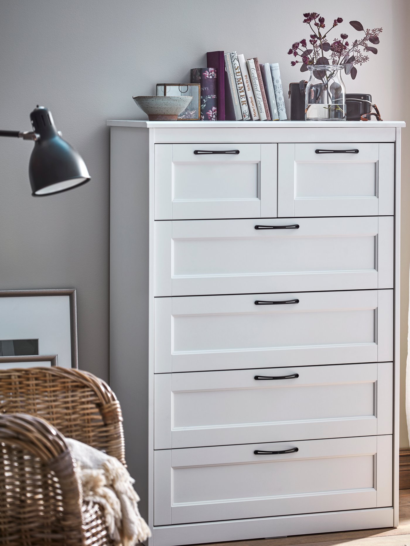 Cómoda SONGESAND blanca de 6 cajones con una planta y libros en su superficie.