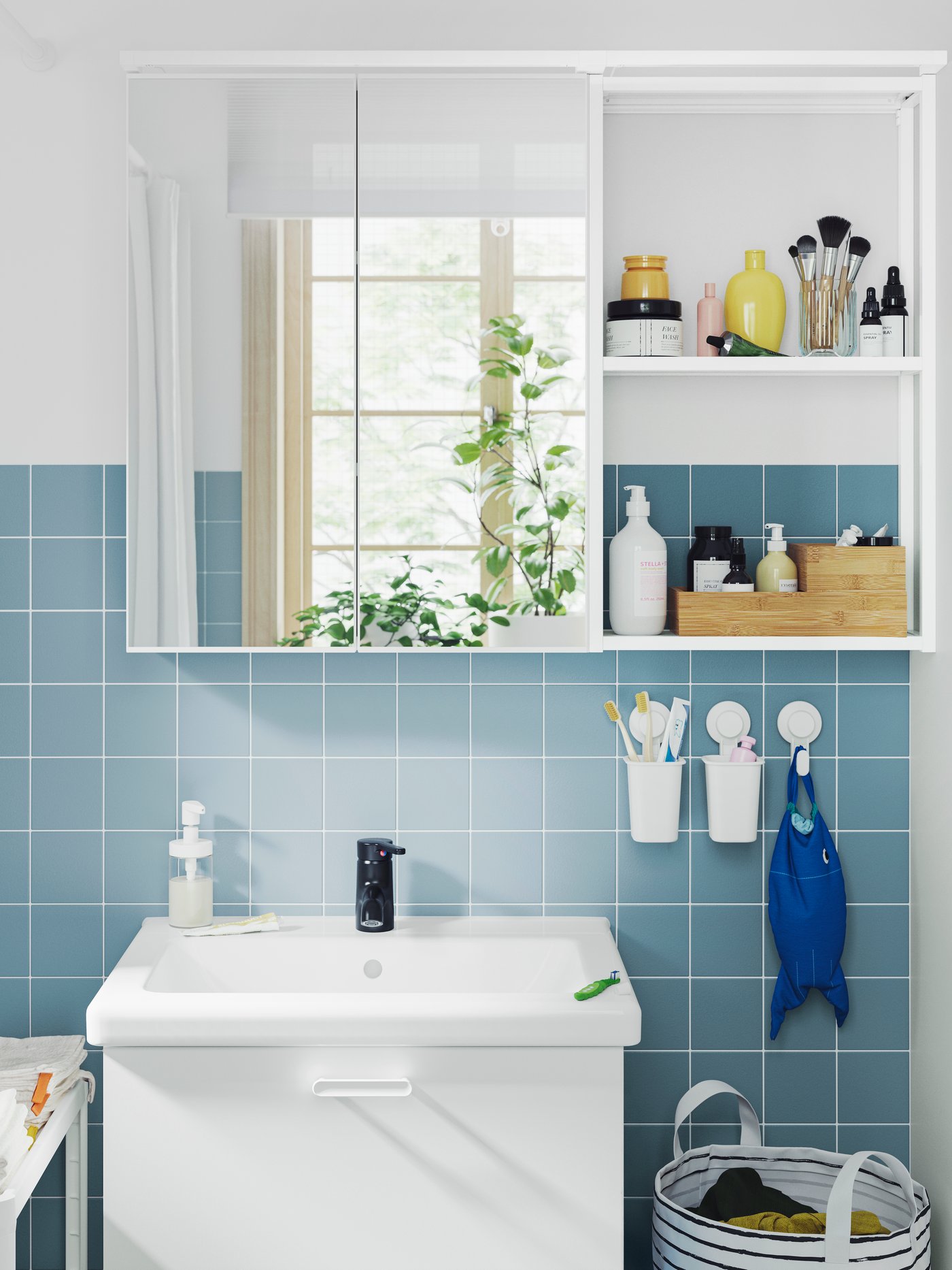 A bathroom has a white ENHET base cabinet, a wall cabinet with mirror doors and a frame with shelves for care products.
