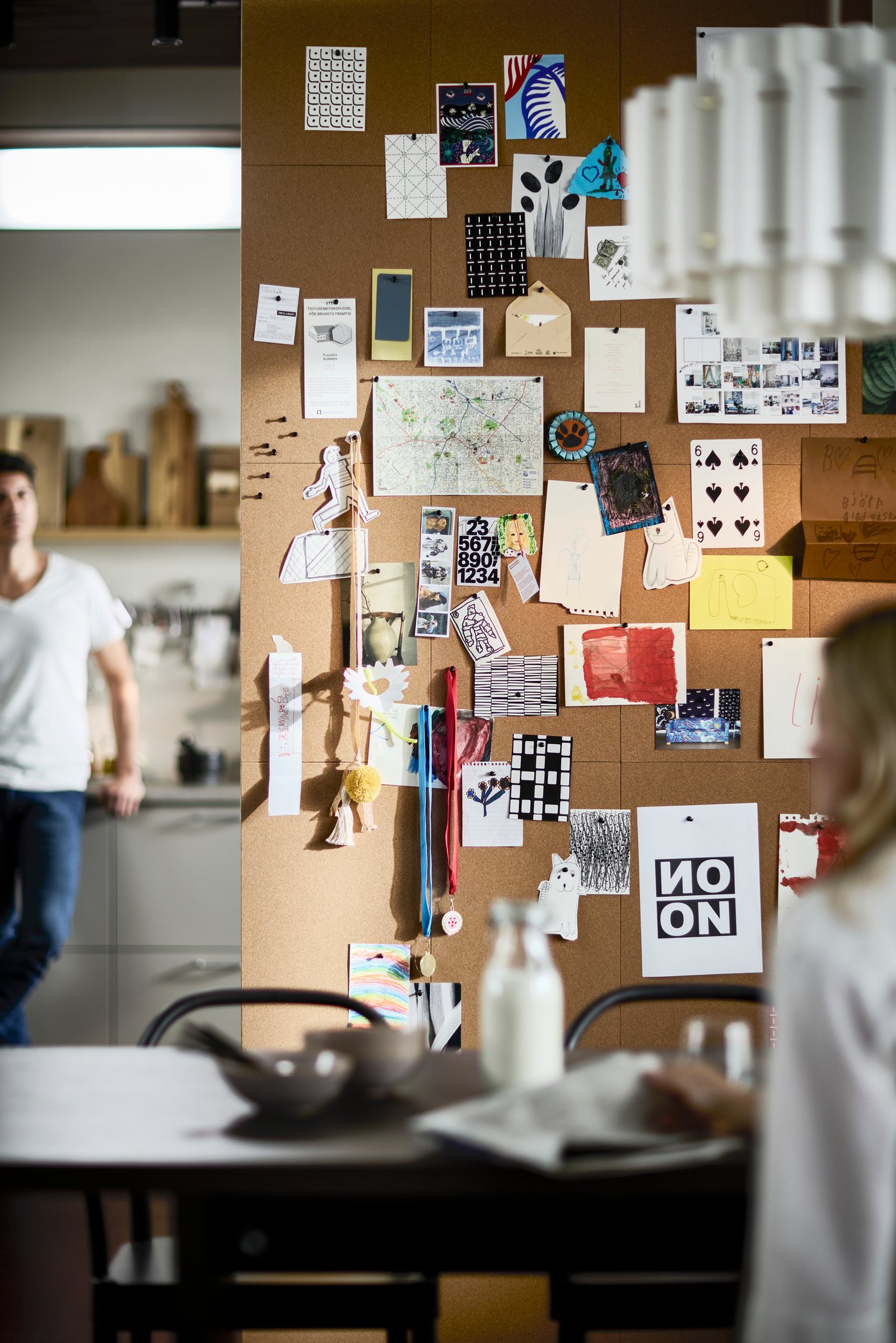 FLÖNSA memo boards in cork used as a large inspiration wall, displaying notes, photos, drawing and small keepsakes in a dining room.				