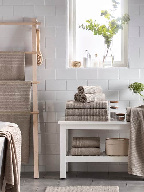 Bathroom featuring a white bench made of solid birch supporting multiple bath towels and an oval storage box with mirror lid.