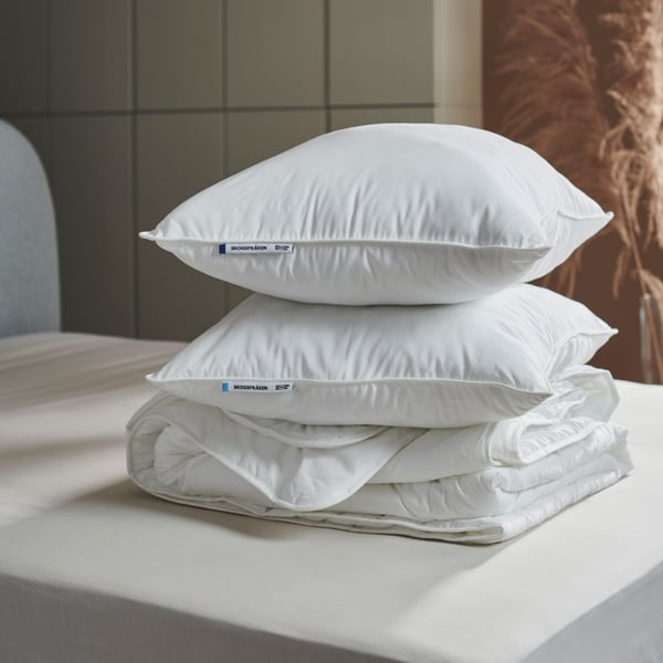 Two high SKOGSFRÄKEN pillows without pillowcases are stacked with a white duvet on a bed, in a modern-style bedroom.