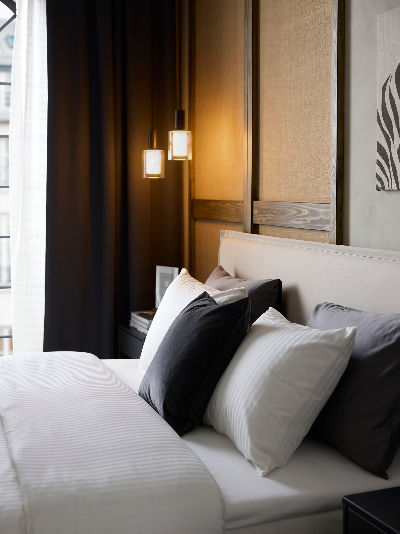 A hotel bed has rows of pillows and white, sateen-woven NATTJASMIN quilt cover and pillowcases that are discreetly striped.