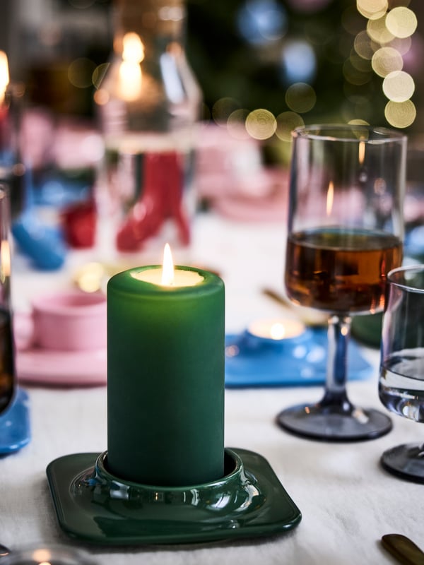 Candelabro verde con una vela encendida verde en su interior.