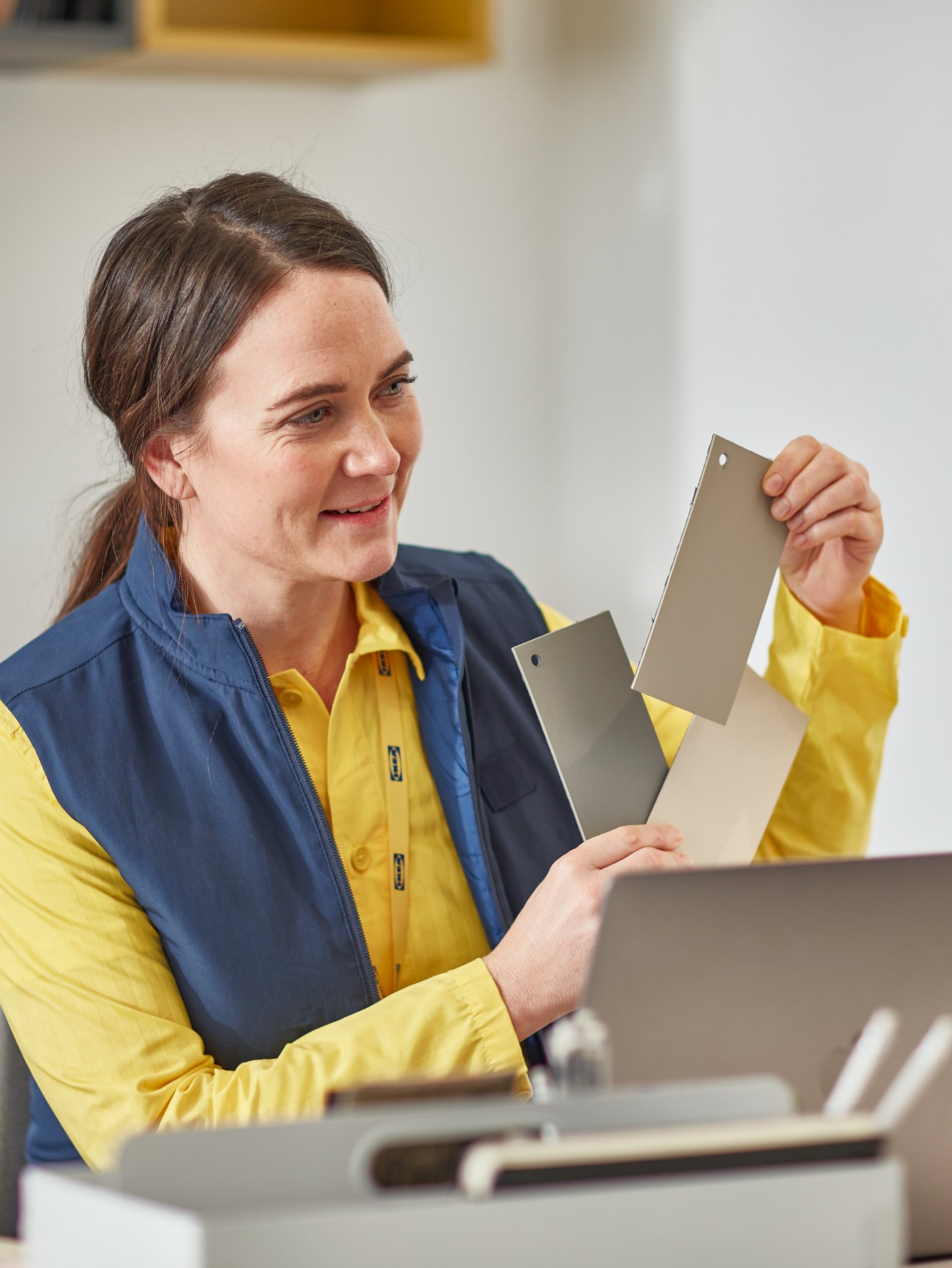 An IKEA employee shows different colour cards to the camera in a video call on a laptop