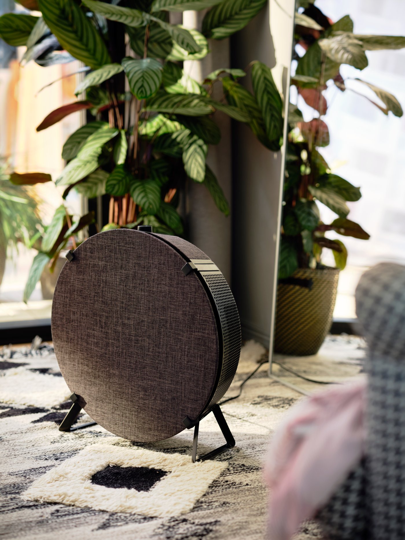Musta IKEA Home smart -ominaisuudella varustettu STARKVIND-ilmanpuhdistin matolla kasvin edessä.