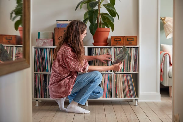 A girl arranging records in a shelving unit.