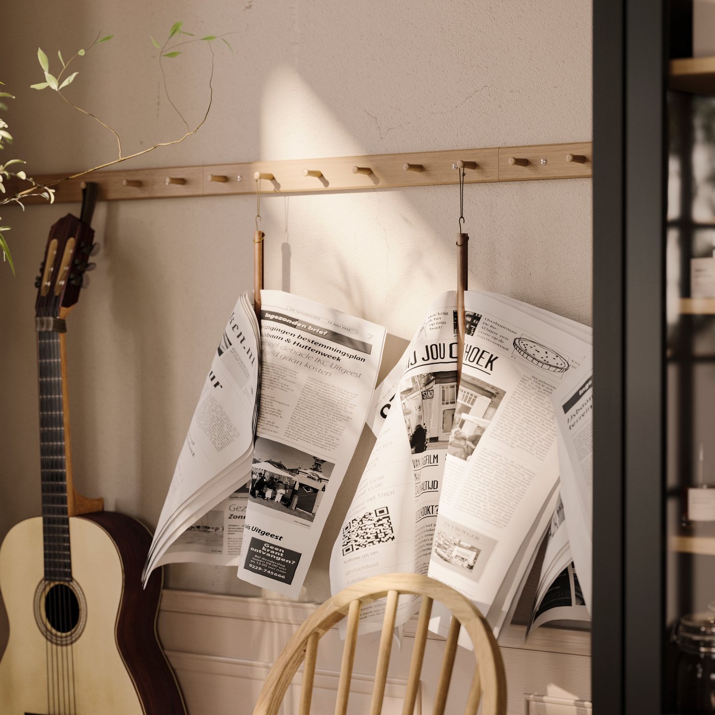 Multiple oak HÖVOLM racks with six knobs are on wall, holding newspapers and an acoustic guitar.