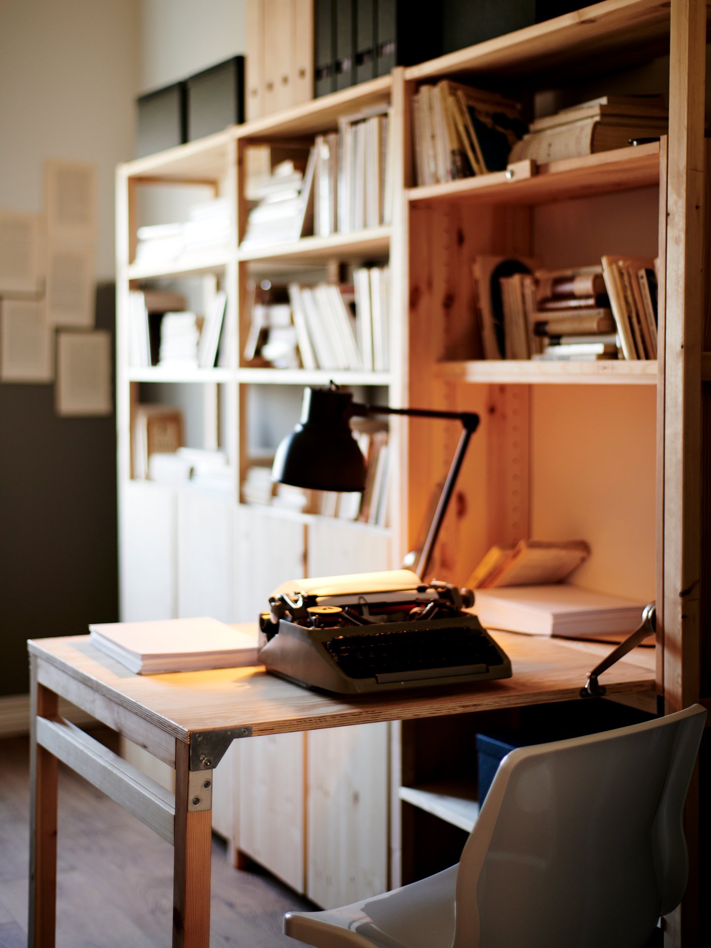 A student room with an open storage unit and a foldable desk with a bookcase in the background.