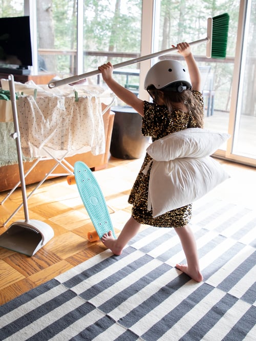 A child wearing a helmet is holding a broom with both hands next to a PEPPRIG dustpan broom, and a JÄLL drying rack.