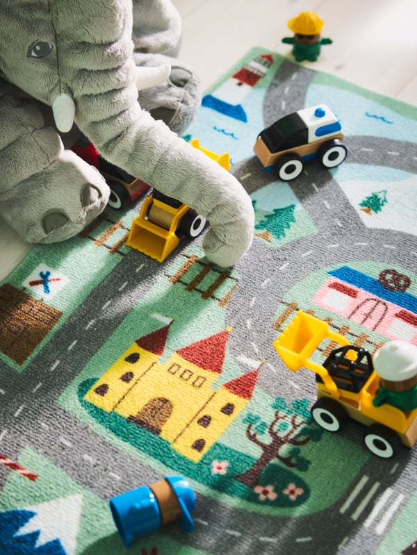 Close-up of VALLABY rug with some toy cars and the big JÄTTESTOR soft toy elephant sitting by it.
