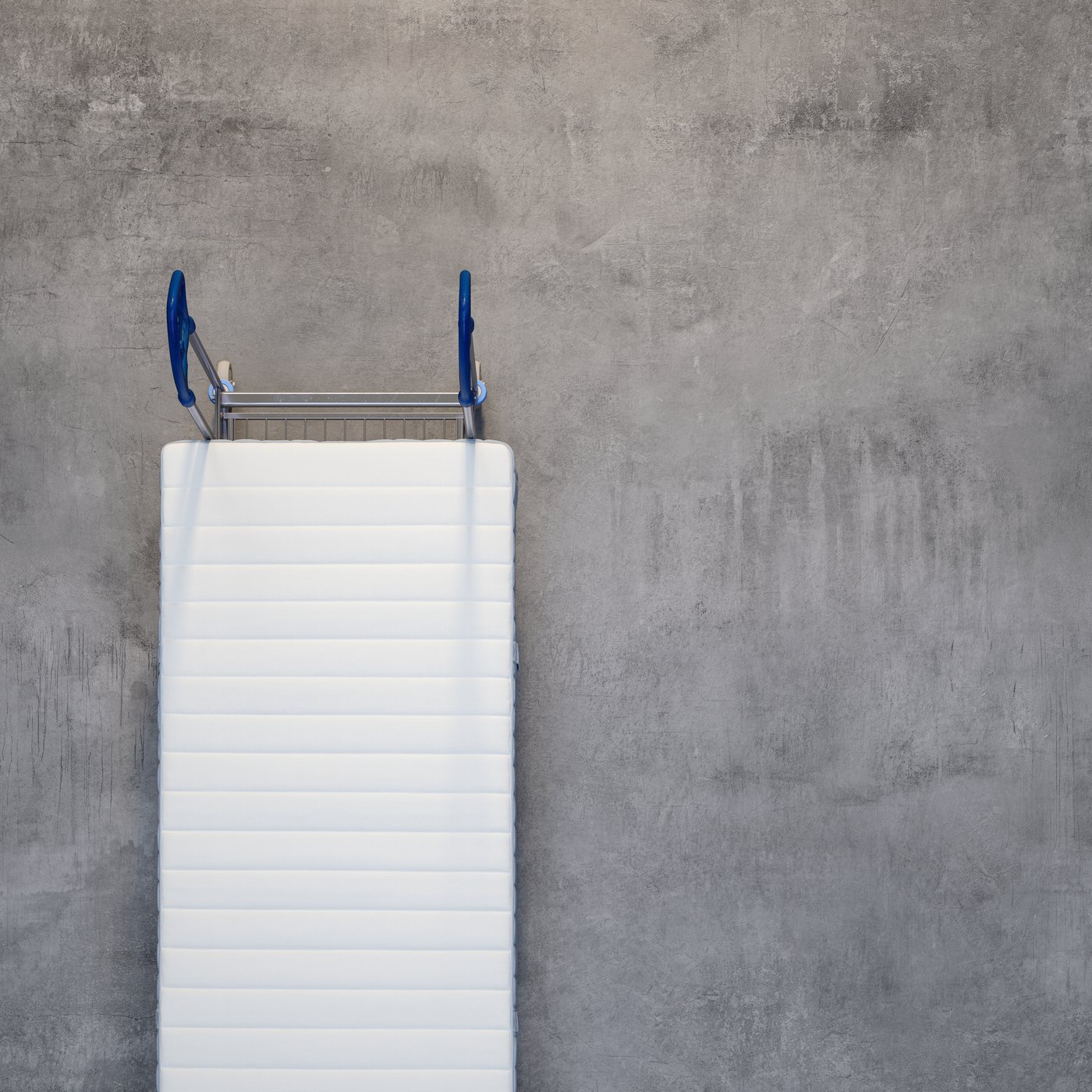 Set ovenfra og ned af en madras på en vogn på et betongulv.