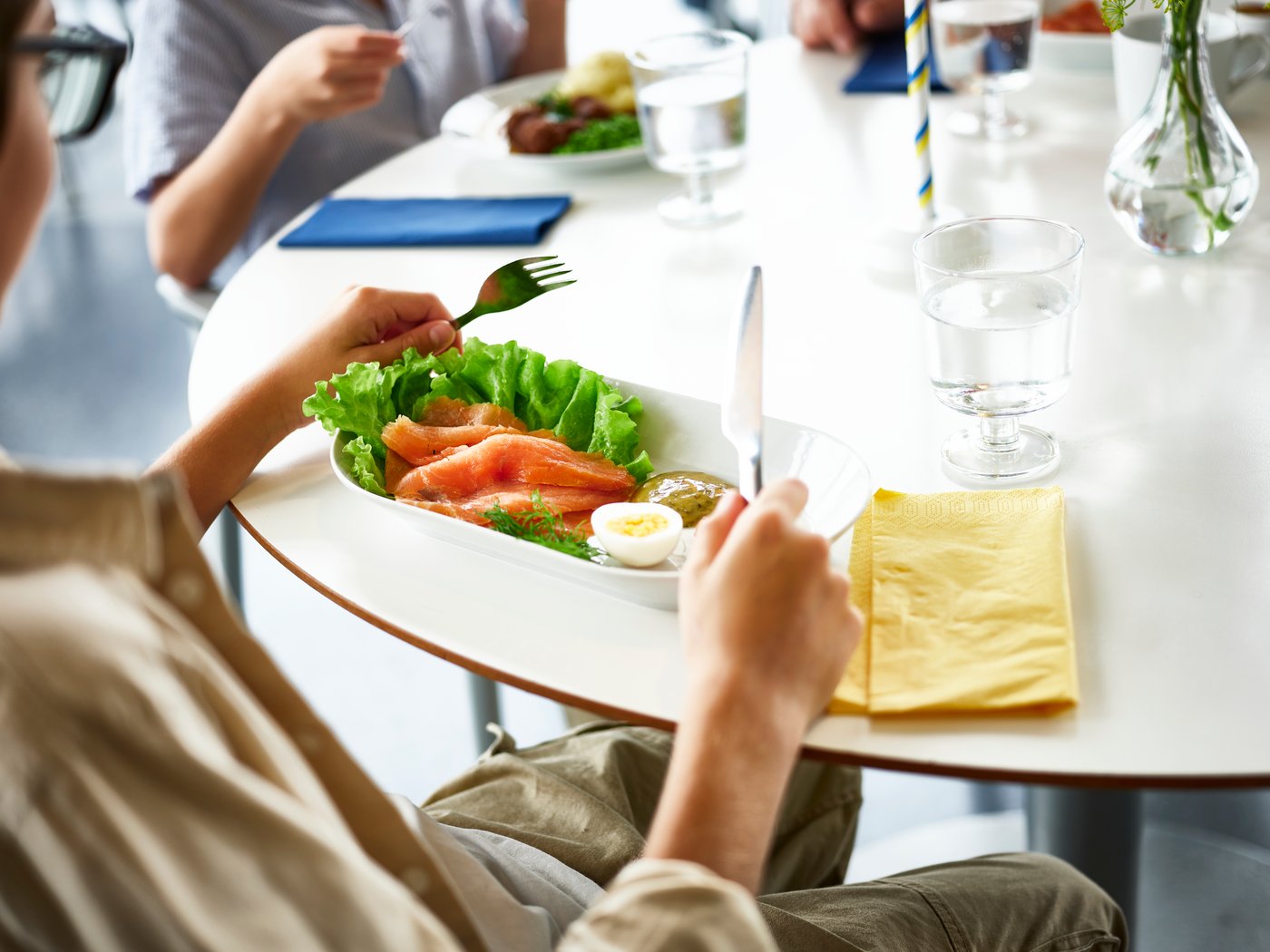 Jed z lososom na mizi poleg osebe, ki bo začela jesti.