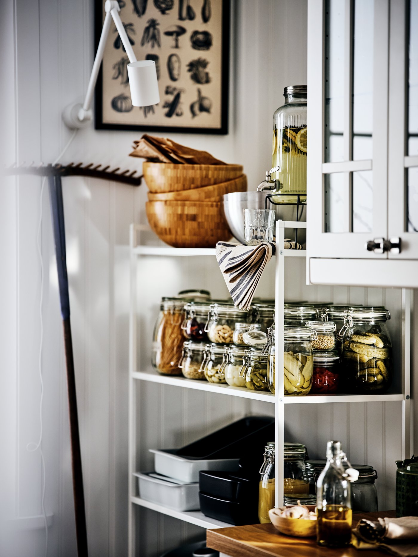 La esquina de una cocina con un mueble de despensa que tiene frascos de vidrio con alimentos no perecibles.