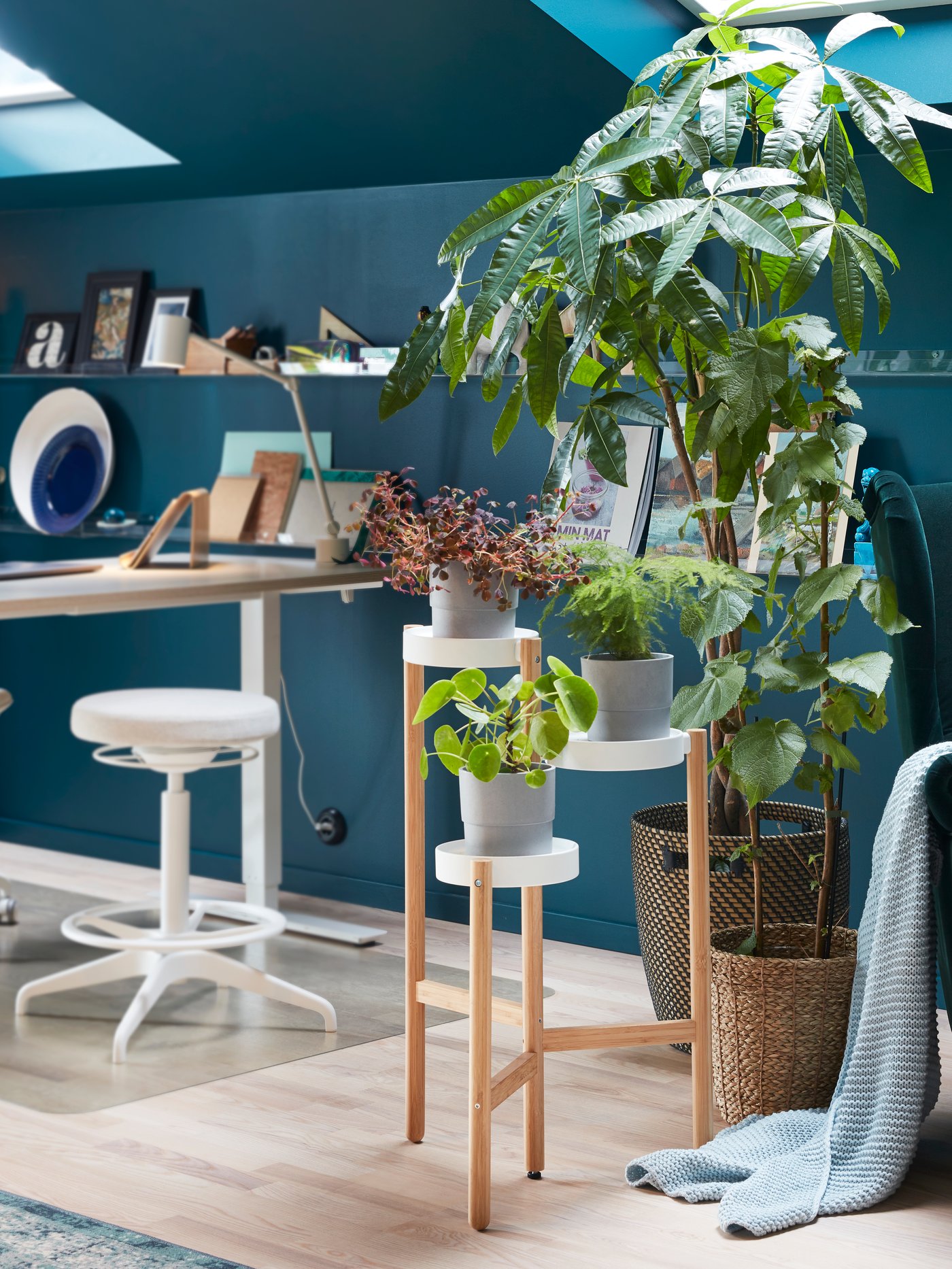 Modern workspace close-up of a beige and white plant stand made out of bamboo on top of a white floor protector.