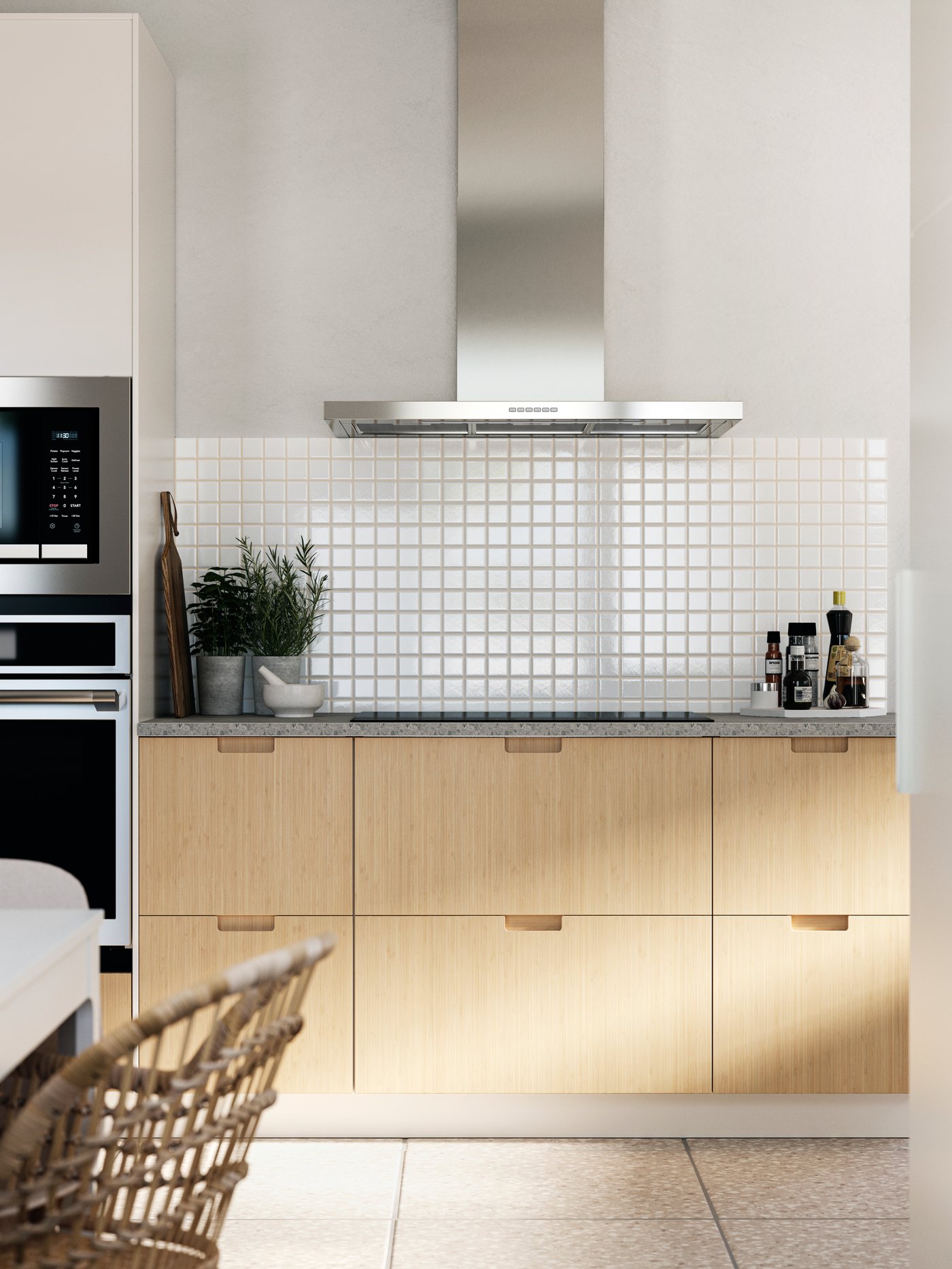 ห้องครัวที่มีผนังสีขาว กระเบื้องสีขาวแผ่นเล็ก หน้าลิ้นชักครัว FRÖJERED/เฟรยเรียด ที่ทำจากไม้ไผ่ และเครื่องใช้ที่ทำจากสเตนเลส