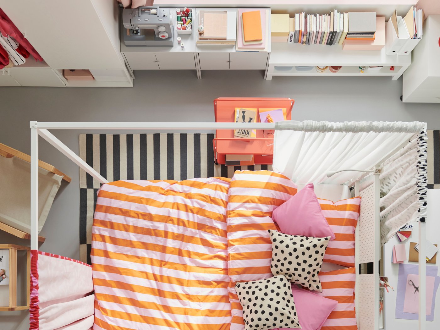 En vy ovanifrån av ett färgstarkt sovrum med en vit VITARNA himmelsäng i mitten, bäddad med SLÅNHÖSTMAL sängkläder.