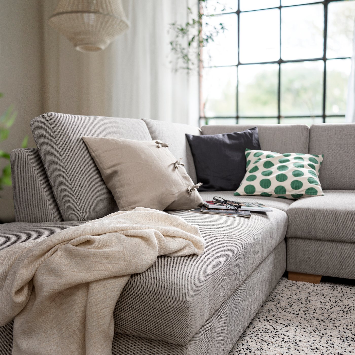 Divano angolare SÖRVALLEN 3 posti con chaise-longue, rivestimento VIARP beige/marrone, in un soggiorno luminoso con cuscini decorativi.