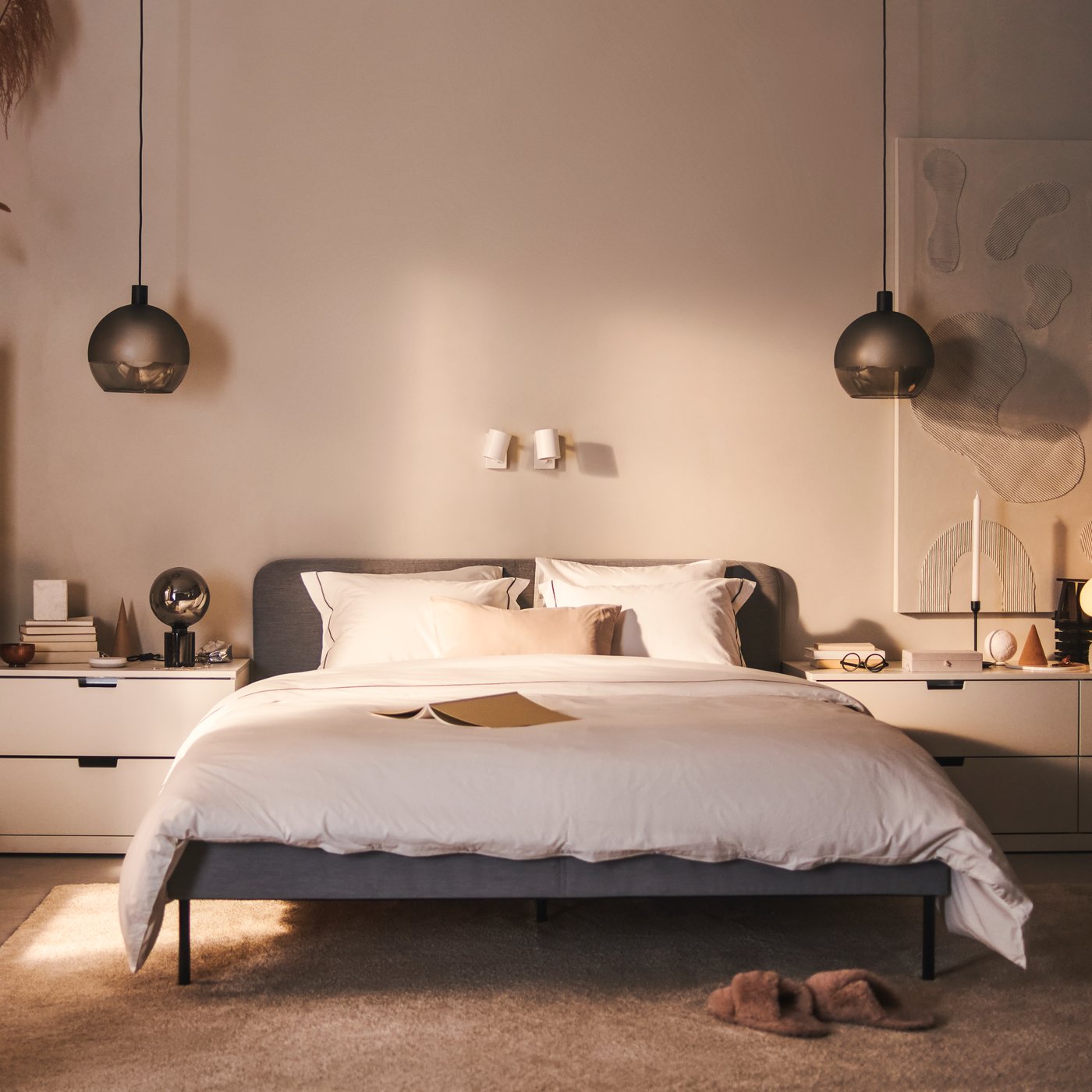 Un letto imbottito SLATTUM e varie cassettiere NORDLI bianche di fronte alla parete di una camera da letto.