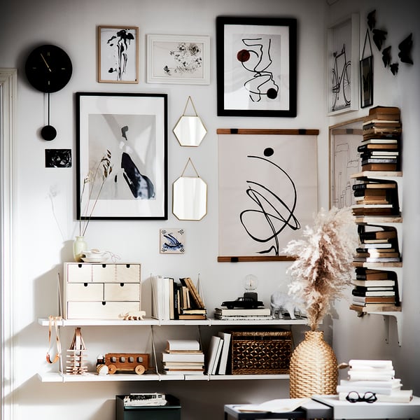 A light room featuring a black-stained EDSBRUK frame displaying various artworks and a serene decorative arrangement.