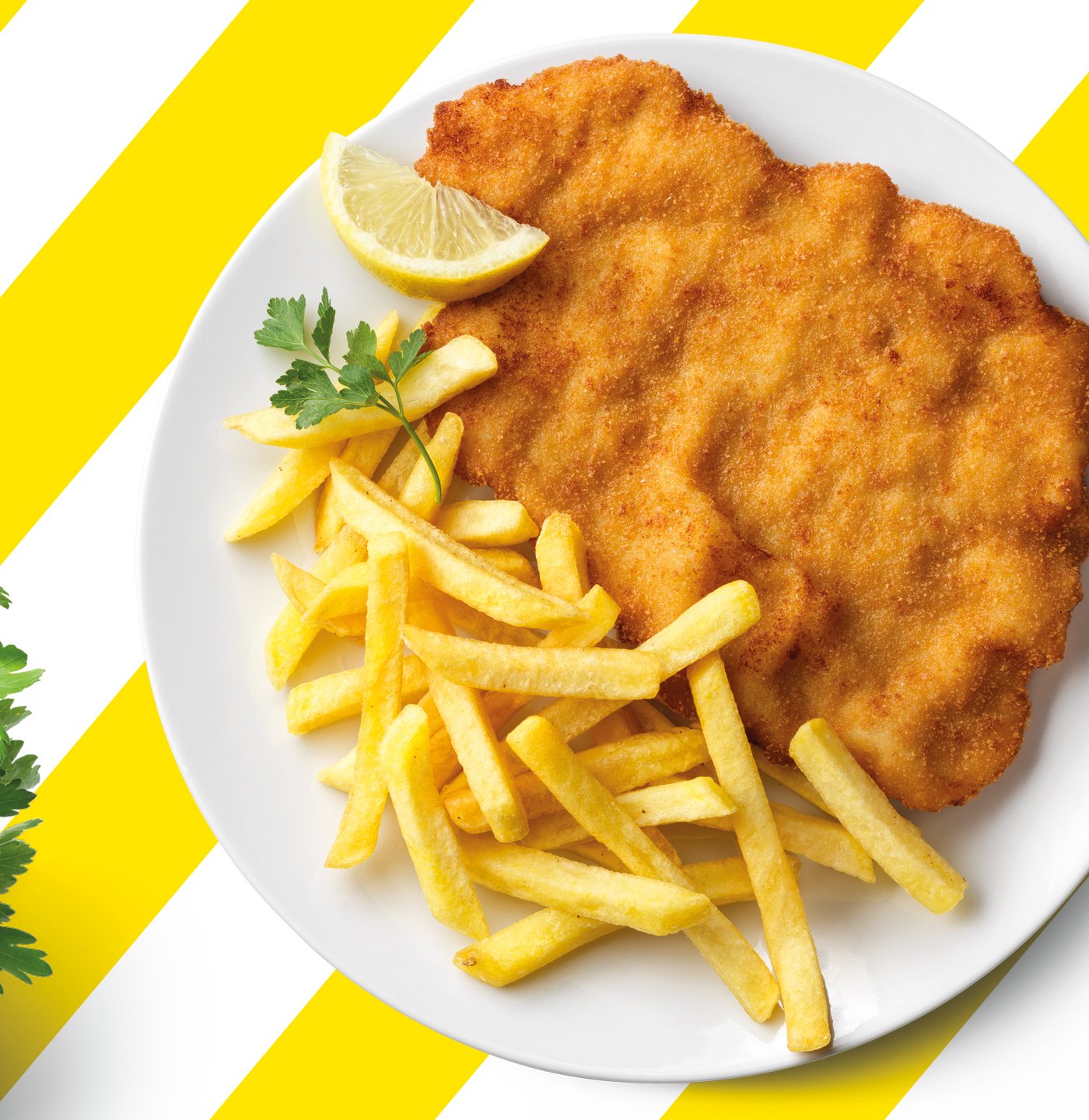 Auf einem weiß-gelb gestreiften Tisch steht ein Teller mit Schnitzel, Pommes und einer Zitrone