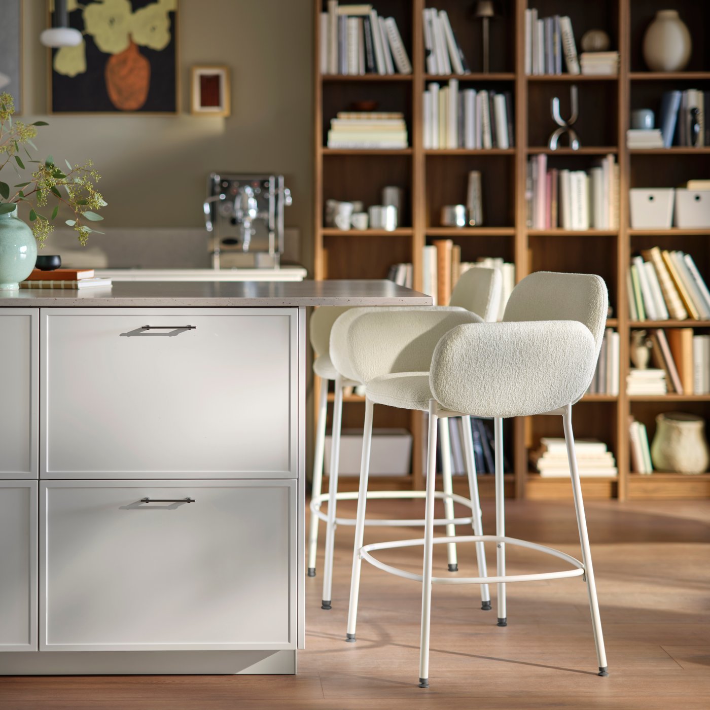 A close up featuring a kitchen island countertop with ajoining two SYNTORP bar stools with bookshelves in the background.