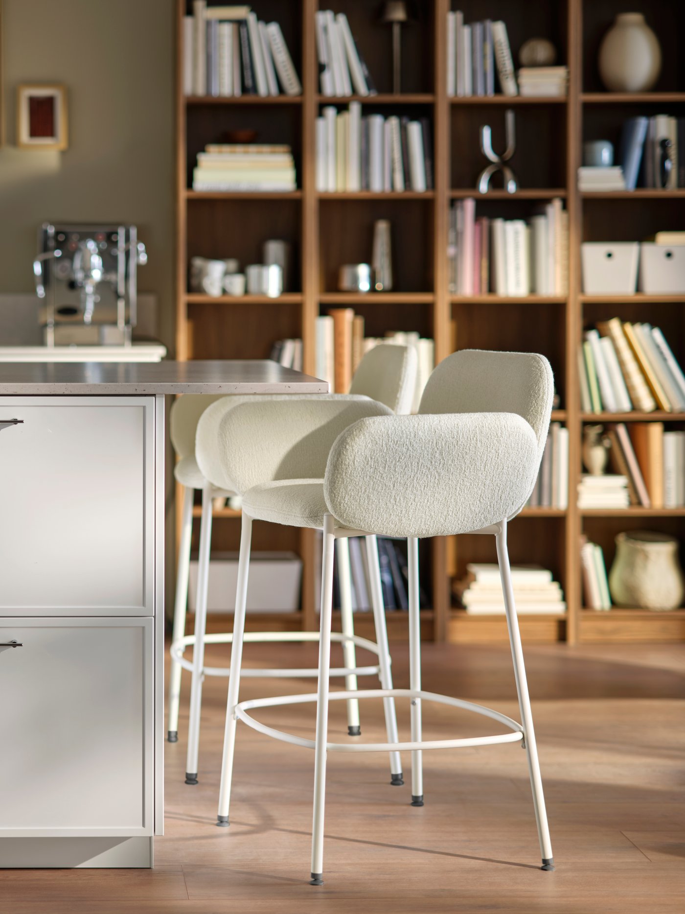 A close up featuring a kitchen island countertop with ajoining two SYNTORP bar stools with bookshelves in the background.