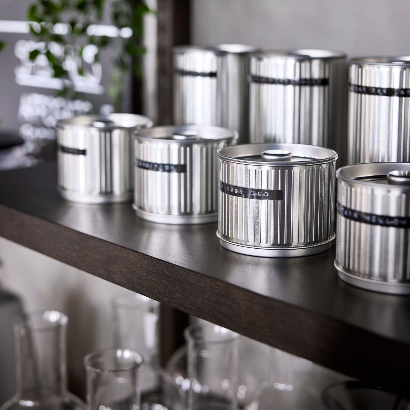 A collection of different-sized silver-colour BETTHAJ tins with lids neatly arranged on a dark wooden shelf.