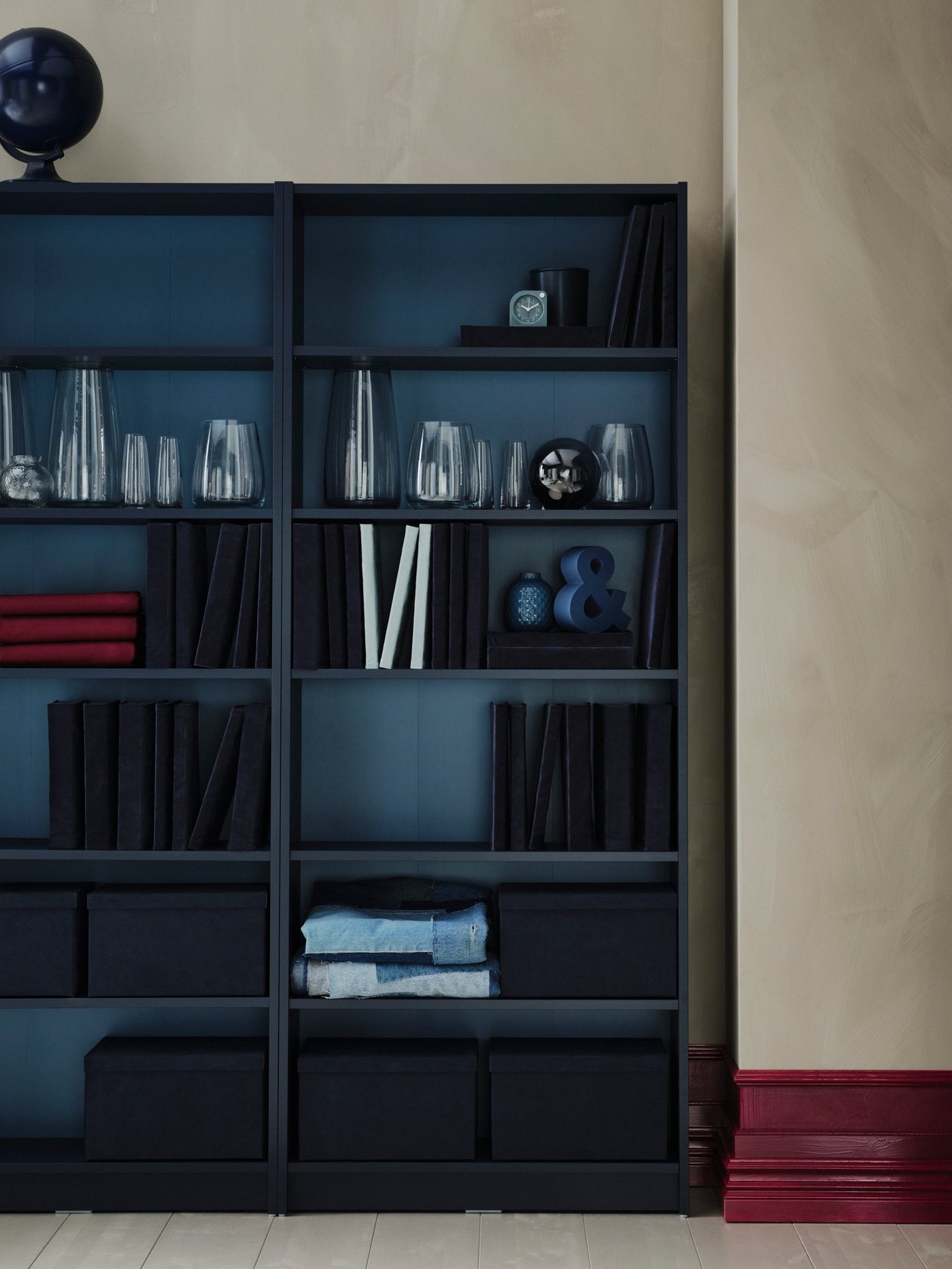 A black BILLY bookcase sits against a light beige wall. The bookshelf is filled with various dark accessories.