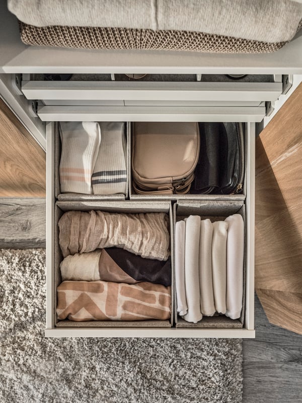 An overhead view of a grey KOMPLEMENT drawer with four grey KOMPLEMENT storage boxes inside holding small clothing items.