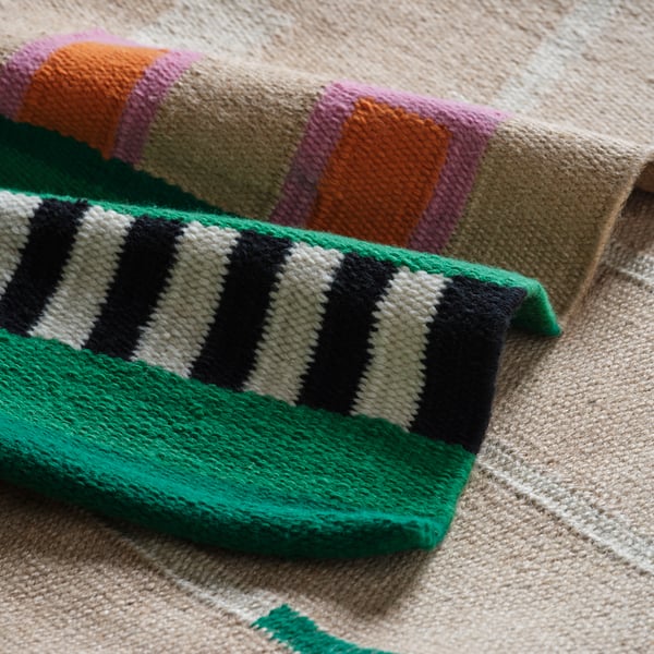 A MÄVINN rug in undyed jute and cotton with stripes in black and white coloured wool with details in green, pink and orange.