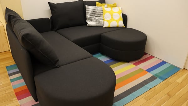 黒いソファとカラフルなラグが置かれているリビングルーム。