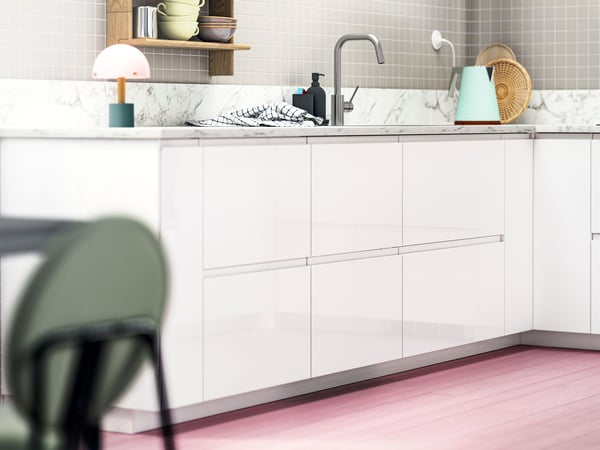 Modern kitchen with VOXTORP high-gloss white fronts, chrome tap, and a small table lamp, styled with decorative accessories.