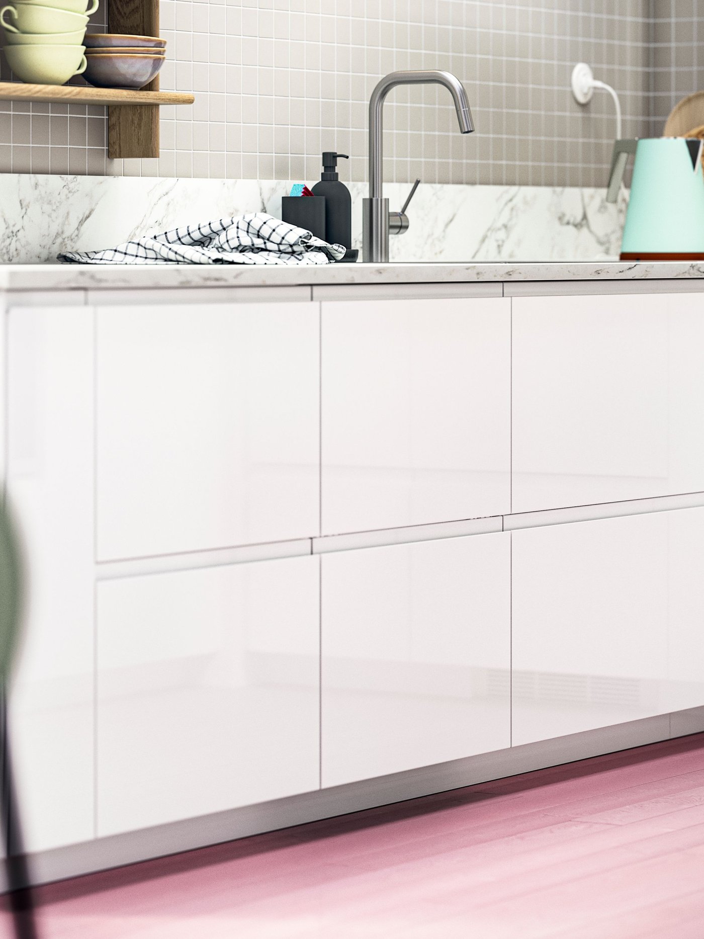 Eine moderne Küche mit VOXTORP Fronten in hochglänzendem Weiß, Böden in Rosa, grünen Stühlen und Farbtupfern in den Regalen.