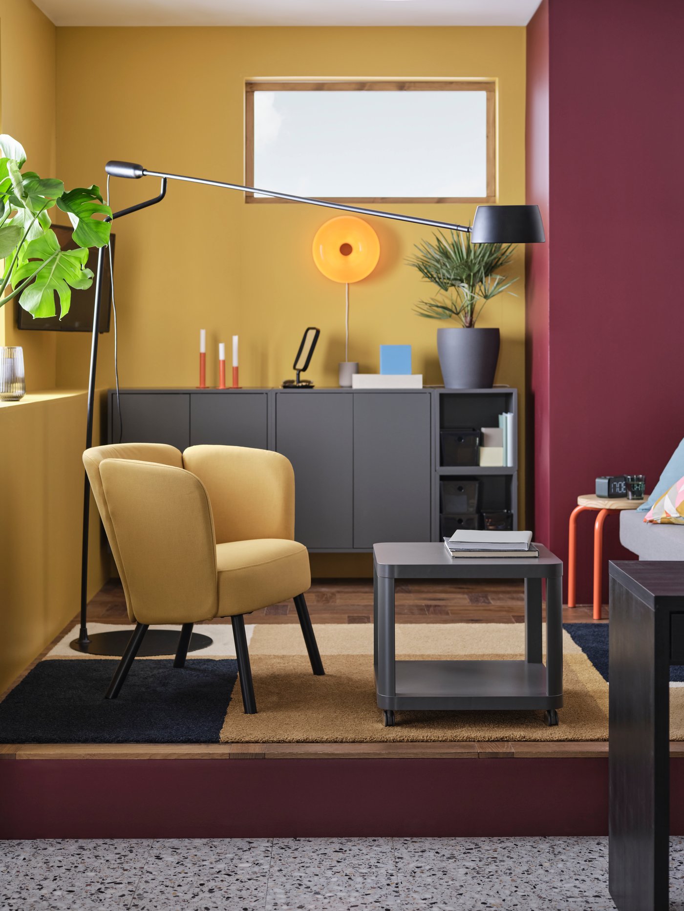 En stue med møbler i moderne stil med minimalistiske grå skabe, en gul lænestol og en væglampe i retrostil.