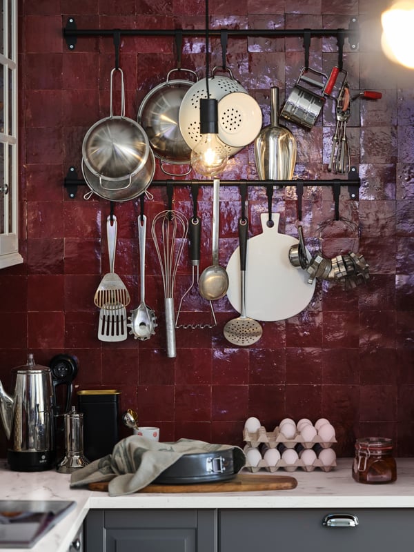 Dapur SEKTION/MAXIMERA dengan rel HULTARP berwarna hitam yang mempunyai periuk dan kuali tergantung padanya dan bekas bentuk spring HEMMABAK berwarna kelabu yang terletak di permukaan atas kerja.