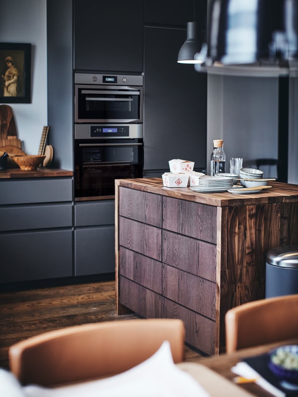 A METOD kitchen with a wooden kitchen island with plates and takeaway food containers on top.