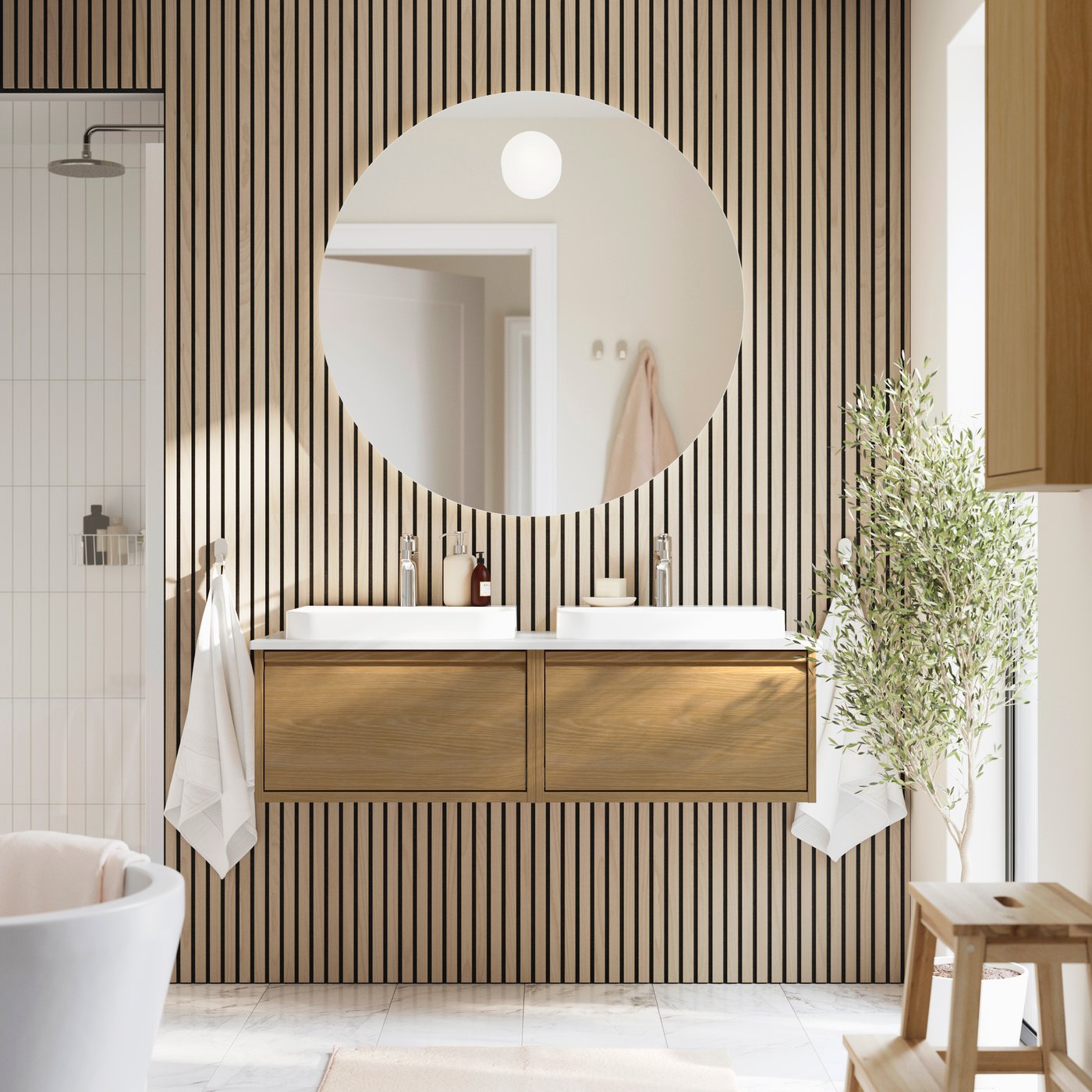 Mueble para lavabo BACKSJÖN con acabado efecto roble y efecto mármol blanco, acompañado de lavabos y grifos a juego en el baño.