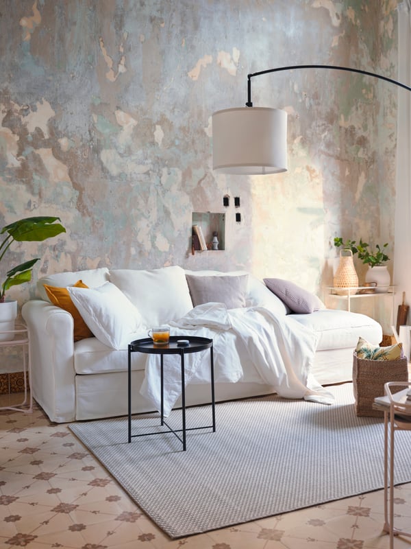 Un living con un sofá blanco de 3 cuerpos sobre una alfombra MORUM .