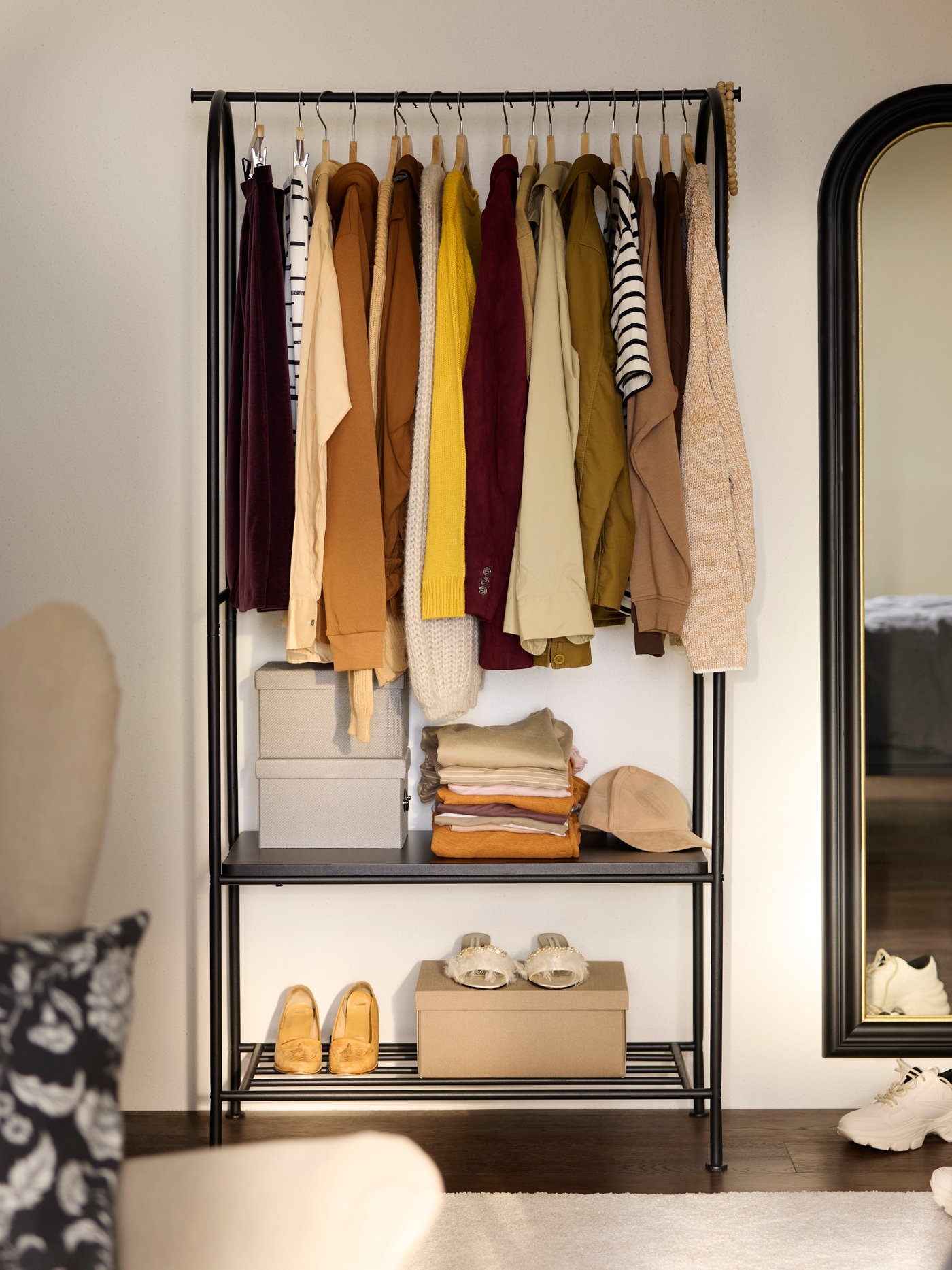 GRÅFJÄLLET clothes rack with shoe storage with clothes in brown and beige neatly hung up, boxes and shoes in same colours.