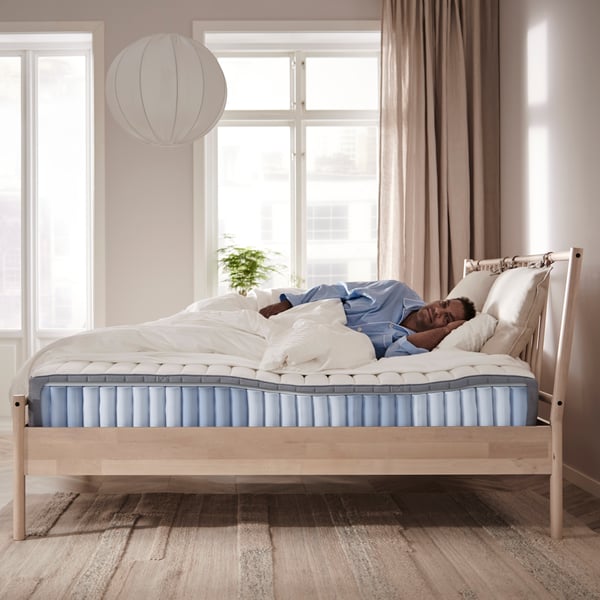 A person laying on a mattress, the side view shows the mattress composition with pocket springs.