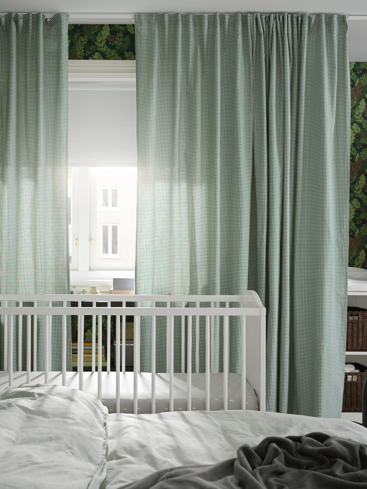 เตียงเด็กอ่อน SMÅGÖRA/สมัวเยอรา ตั้งอยู่ถัดจากเตียงคู่ SAGSTUA/ซ้ากสตัว ใกล้กับหน้าต่างที่ติดผ้าม่าน ORDENSFLY/ออร์เดนสฟลาย และม่านม้วน FRIDANS