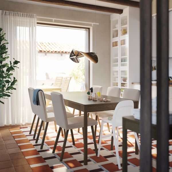A dining room has a TONSTAD extendable table in brown stained oak veneer with six chairs and a cabinet with glass doors.
