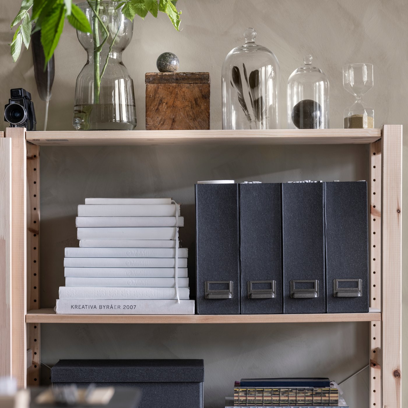 Satu bahagian bagi unit rak IVAR buatan pain yang diletakkan tempat letak majalah diatur secara kemas, buku, kubah kaca dan hiasan lain.