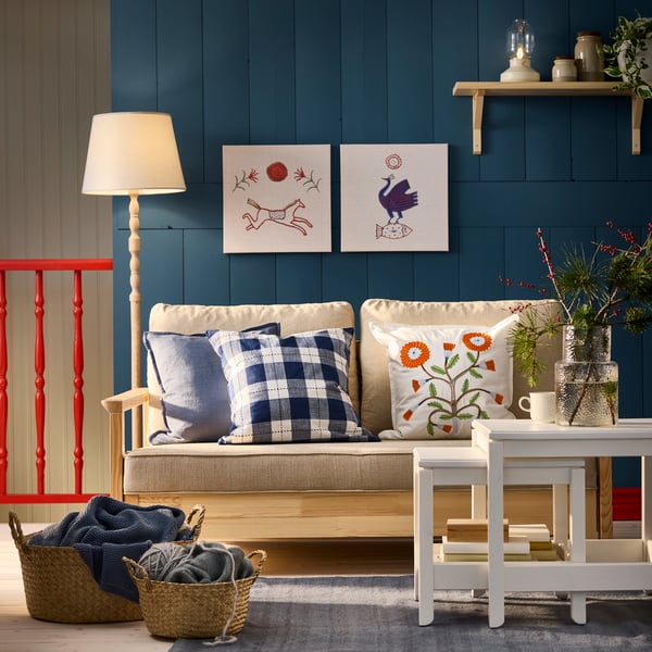 A cosy living room with a TORNSBORG 2-seat sofa-bed and a FACELIOR cushion cover featuring a dark orange embroidered pattern.