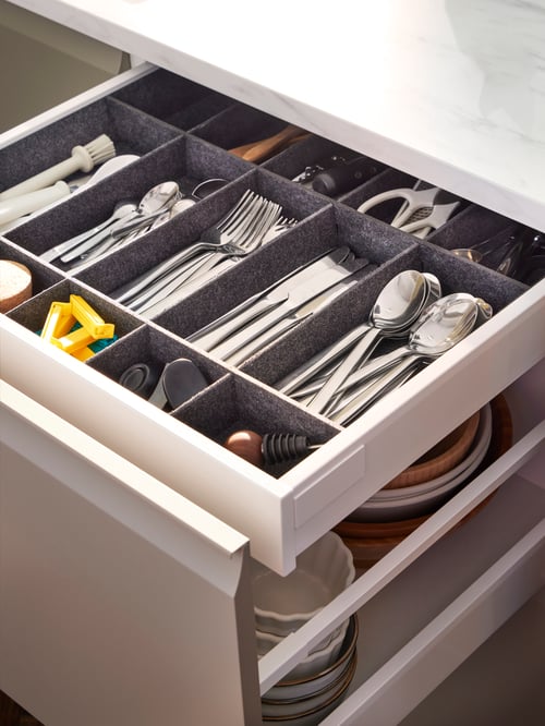 Kitchen featuring a grey UPPDATERA adjustable organiser for drawer storing a grey IKEA 365+ 56-piece cutlery set.
