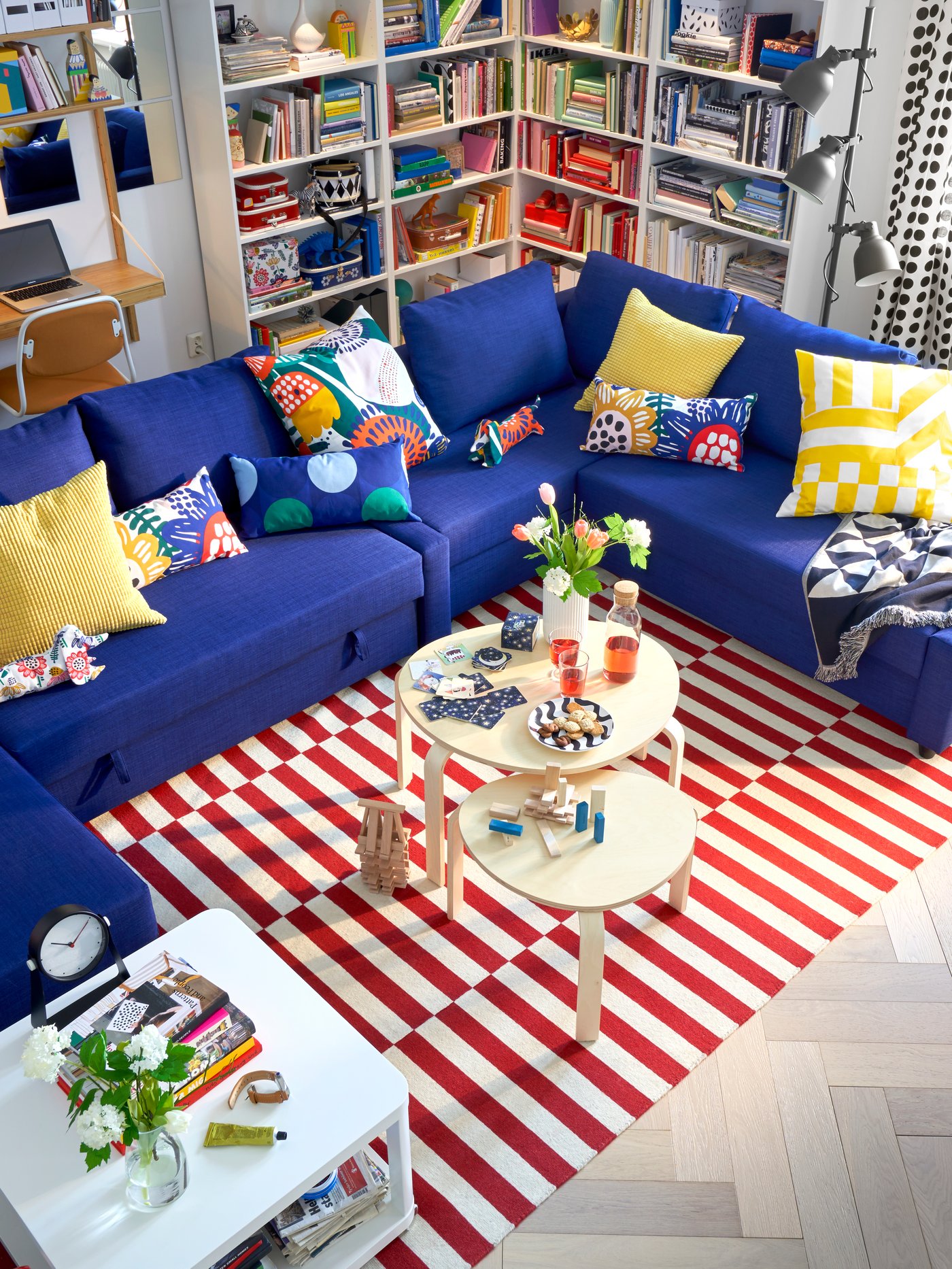 A blue corner sofa with lots of white BILLY bookcases in the living room.